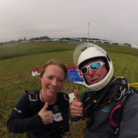Mark and skydiving student gives thumbs up in landing area after making skydive