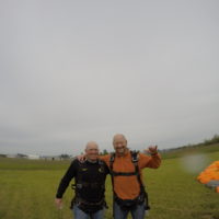 man and his instructor hug and smile after landing from tandem skydive