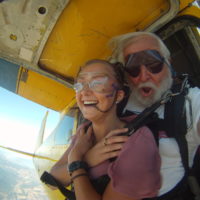 woman smiles and crosses her arms over her chest before exiting skydiving aircraft