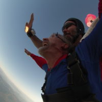 man looks up at the sky and smiles during freefall