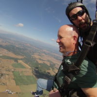 man smiles excitedly after skydiving canopy deploys