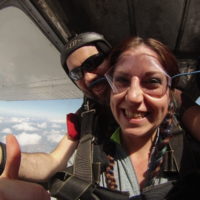 young woman smiles with instructor before exiting skydiving plane