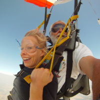 blond woman smiles under canopy making first ever tandem skydive