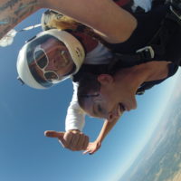 Mark gives thumbs up while in freefall with tandem skydiving student
