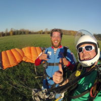 tandem skydiving student smiles and gives thumbs up in landing area at Eugene Skydiveres