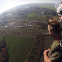 tandem student soars over landing area during sunset at Eugene Skydivers
