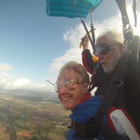 older woman smiles under canopy after making tandem skydive